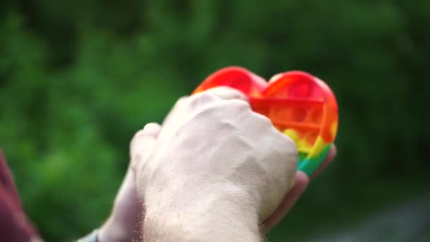 Mann spielt mit Spielzeug Pop es einfach Grübchen sitzen im Park — Stockvideo