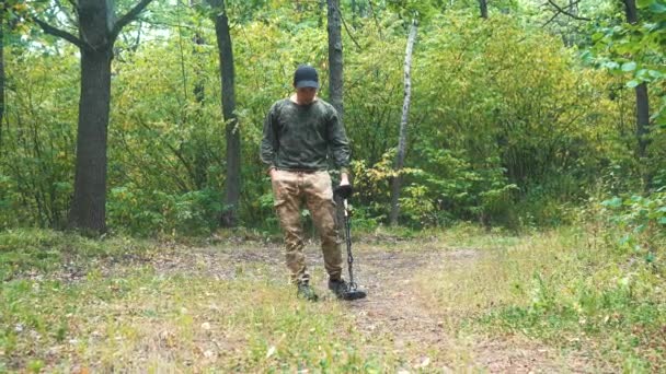 Hombre camina con un detector de metales a través del bosque — Vídeos de Stock