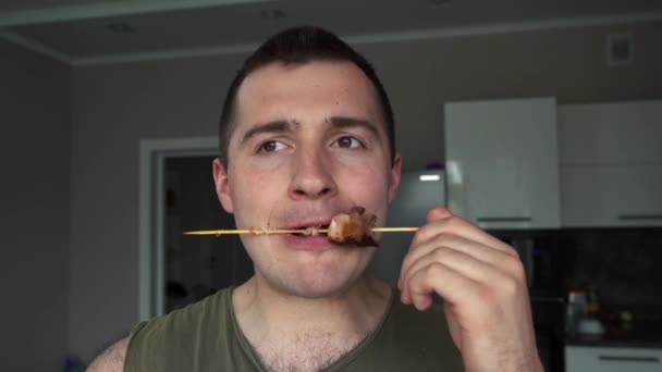 한 남자가 카메라 앞에서 스쿠터를 들고 바베큐를 먹는다 — 비디오