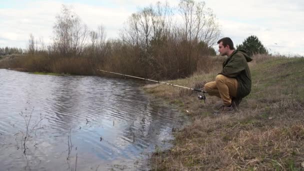 Samec rybáře stojí u řeky a chytá ryby — Stock video