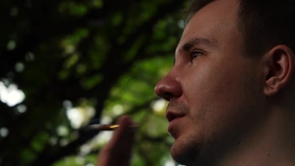 Muž kouří cigaretu, zatímco v lese — Stock video