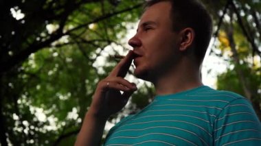 Bir adam sokakta dikilirken sigara içiyor.