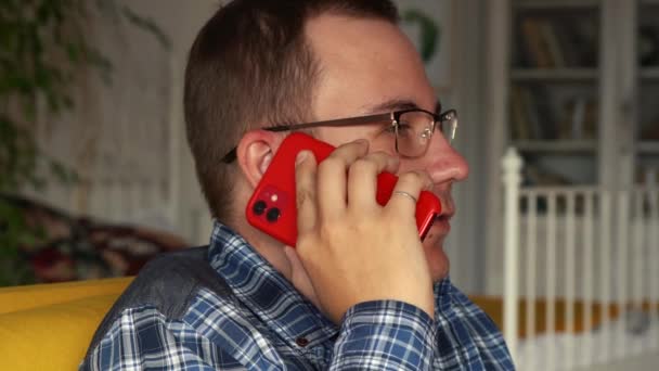 Retrato de un hombre hablando por teléfono sentado en el sofá en casa — Vídeos de Stock