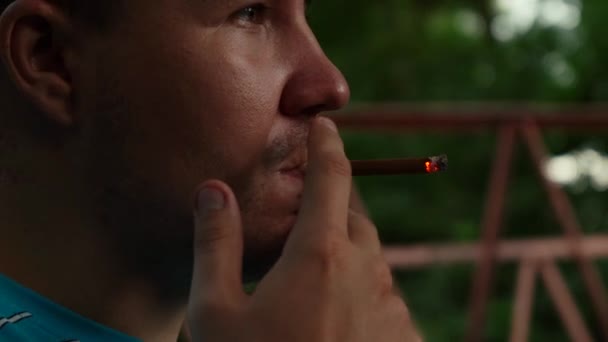 Un hombre fuma un cigarrillo mientras está en la calle — Vídeos de Stock