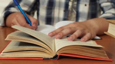 Gömlekli bir adam bir kitaptan not alır.