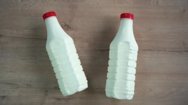 Deux bouteilles de lait couchées sur une table en bois — Video