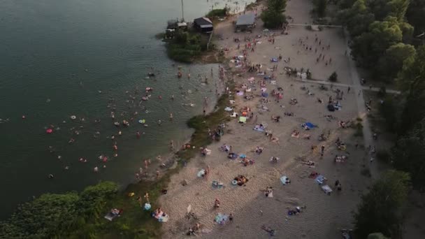 Dron filmando una playa de arena llena de gente junto al lago. — Vídeos de Stock