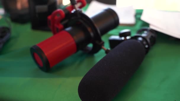 Настольные микрофоны лежащие на зеленом столе — стоковое видео
