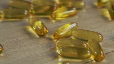 Omega 3 balık yağı kapsülleri ahşap bir masada yatıyor..