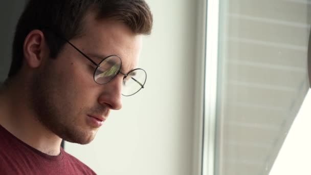 Mann mit Brille blickt misstrauisch aus dem Fenster — Stockvideo