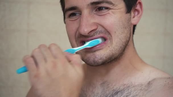 Naakte man poetsen tanden terwijl staan in de voorkant van de badkamer spiegel — Stockvideo