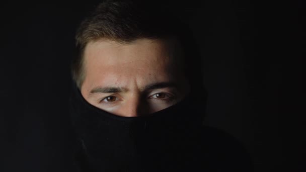 Man gangster neemt af zijn masker op een zwart achtergrond. — Stockvideo