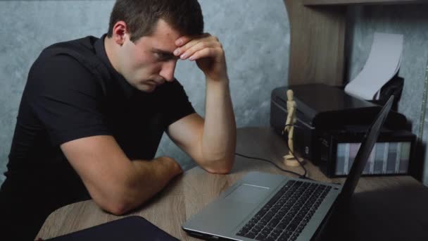 Κουρασμένος άνθρωπος κάθεται εργασίας στο φορητό υπολογιστή — Αρχείο Βίντεο