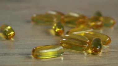 Omega 3 balık yağı kapsülleri ahşap bir masada yatıyor..