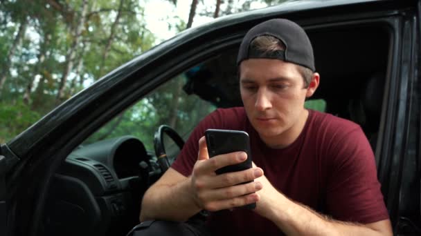 Man smokes vape and uses the phone while sitting in the car. — Stock Video