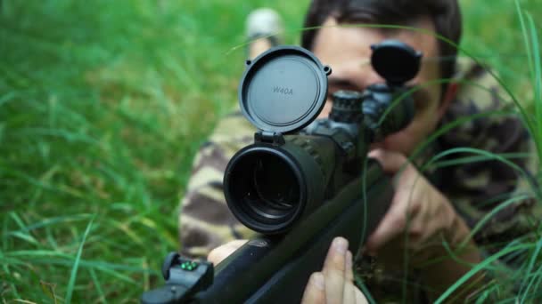 Francotirador masculino mirando a través del alcance de su rifle de francotirador — Vídeo de stock