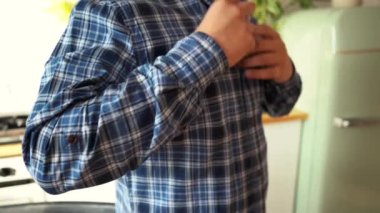 Adam düğmelerini açar ve gömleğini çıkarır.