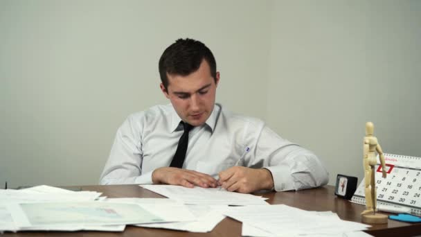 Man fills out documents while sitting at a table in an office — Stock Video