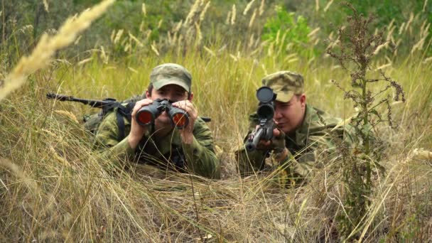 Francotirador con un artillero están sentados en emboscada en los arbustos — Vídeos de Stock