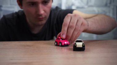 Yetişkin bir adam masada arabalarla oynuyor.