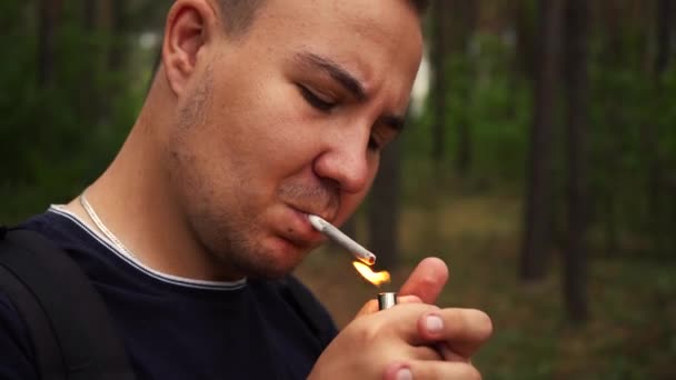 Man steekt een sigaret aan in het bos — Stockvideo