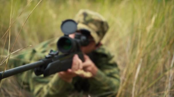 Солдат целится из снайперской винтовки, лежащей в кустах — стоковое видео