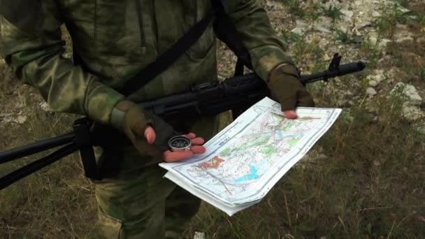 Soldado con una ametralladora mira un mapa de la zona — Vídeo de stock