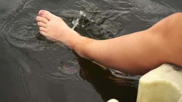 Ragazza immerge i piedi in acqua mentre seduto sul bordo del ponte — Video Stock