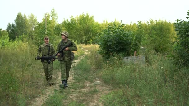 Soldados com armas estão andando ao longo de uma estrada de terra na floresta — Vídeo de Stock