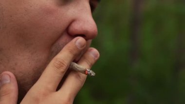 Adam ormanda dikilirken sigara içiyor.