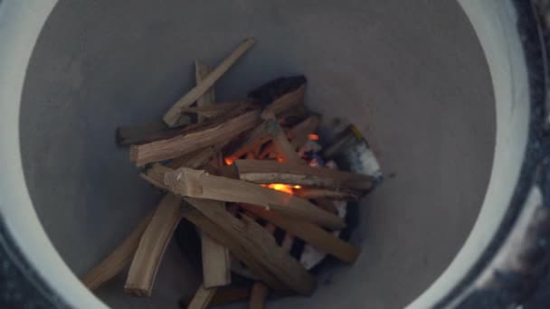 Muž hodí dříví do hořícího tandoor — Stock video