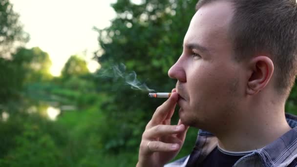 Mannen röker en cigarett när han står med ryggen mot kameran — Stockvideo