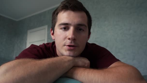 De man praat met de camera terwijl hij in zijn kamer is. 4k-beelden — Stockvideo