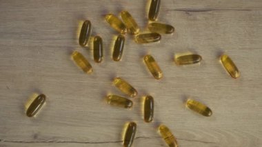Sarı omega 3 kapsülleri ahşap bir masada yatıyor.