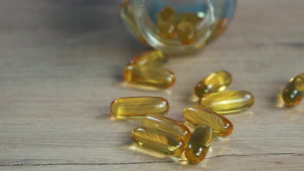 Omega 3 cápsulas de aceite de pescado de oro acostado en la mesa — Vídeos de Stock