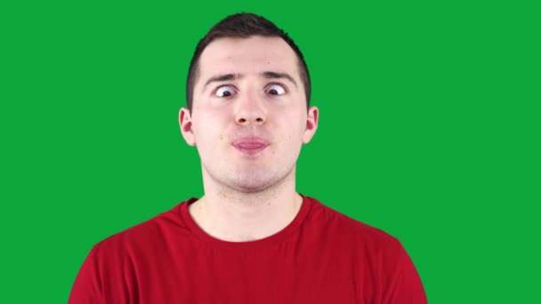 Man grimaces at the camera while standing against the background of a green chroma key — Stock Video