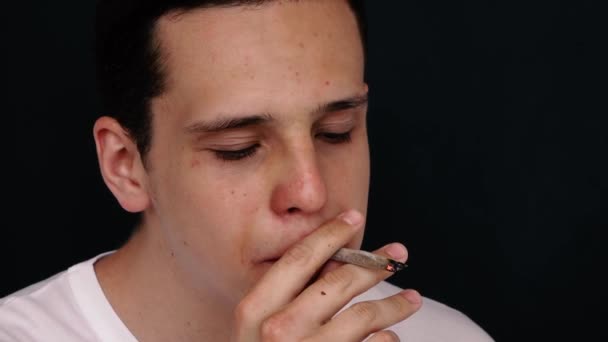 Man smokes a cigarette in slow motion on a black background — Stock Video