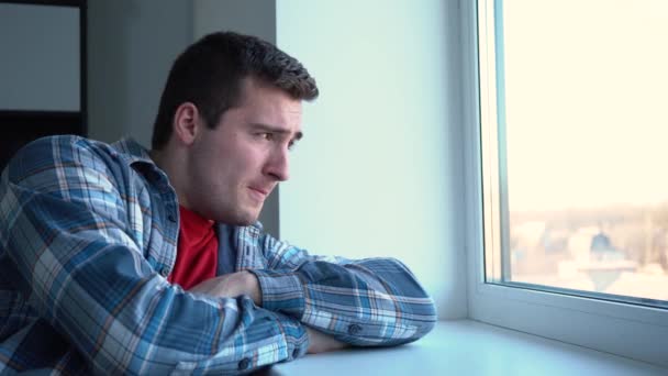 Mann niest, während er auf der Fensterbank sitzt 4K-Video. — Stockvideo