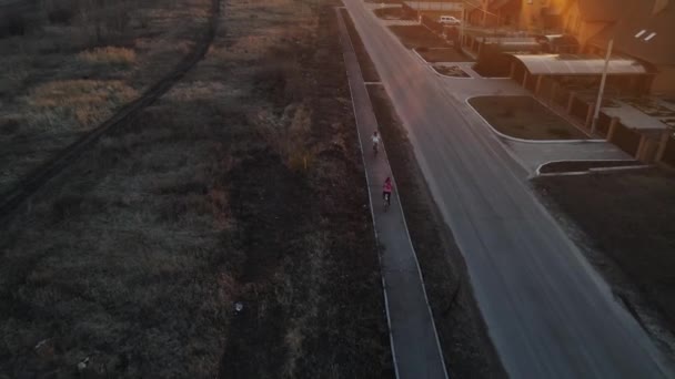 Las niñas montan en bicicleta en la carretera. disparos aéreos — Vídeos de Stock