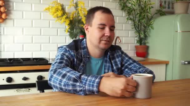 Hombre con camisa está bebiendo té mientras está sentado en la mesa en la cocina. moscow russia 26 julio 2021 — Vídeo de stock