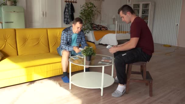 Twee mannen zitten aan een ronde tafel en tellen geld — Stockvideo