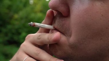 Adam ev yapımı sigara içiyor. Yakından.