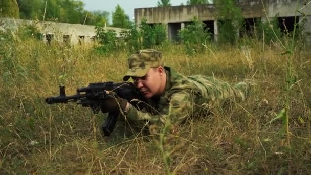 Soldado em camuflagem mira com uma espingarda em posição propensa — Vídeo de Stock