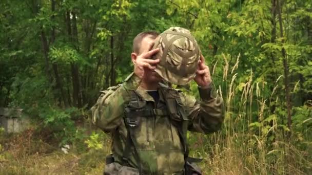 Soldado coloca um capacete na floresta antes de lutar — Vídeo de Stock