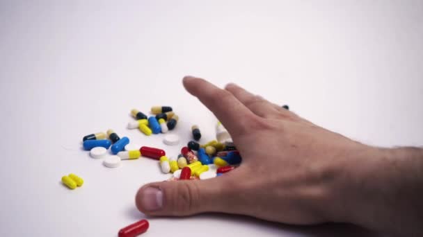 Un hombre toma un puñado de pastillas en su mano sobre un fondo blanco — Vídeos de Stock