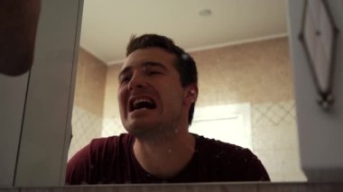 Adam pis bir aynada dişlerini inceliyor.