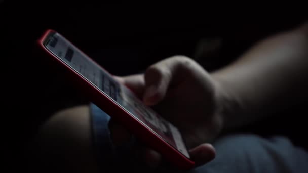 En mann bruker telefon i et mørkt rom. 4k-opptak – stockvideo