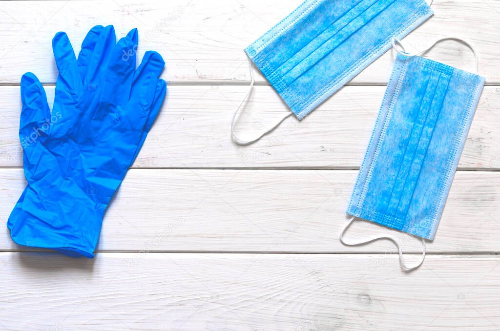 A pair of thin blue medical latex gloves and face shield on a white background. Disposable rubber medical gloves and mask. Protective subjects