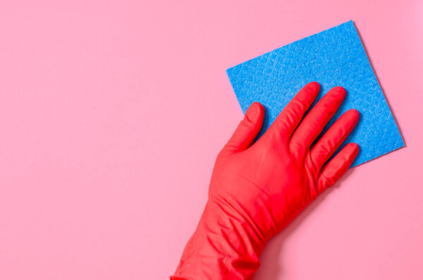 Blue house cleaning sponge in hand in red rubber glove on red background. Commercial cleaning company concept