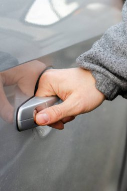 Adamın eli gümüş renkli arabanın kapısını araladı. Yakın plan.